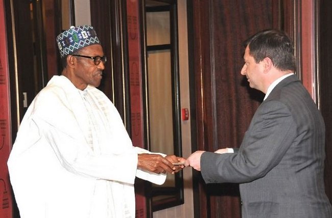 President Muhammadu Buhari receives a document from Paul Arkwright