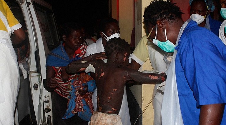 A victim of the fuel tanker in Mozambique helped off an ambulance by health workers