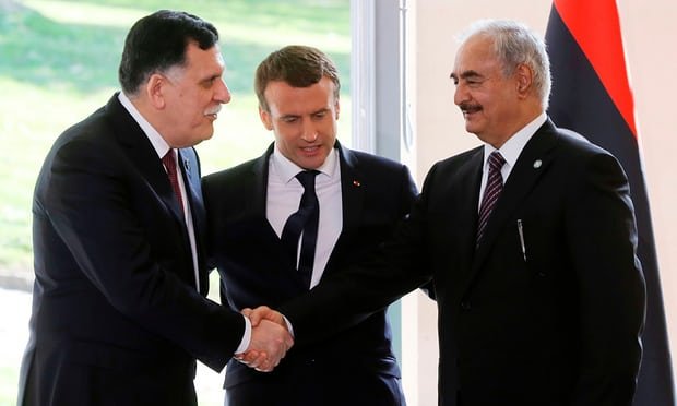 Emmanuel Macron, centre, with Sarraj, left, and Haftar as they shake hands after talks aimed at easing tensions.