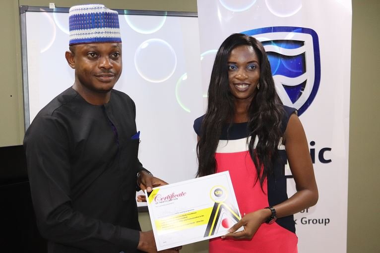 Usman Imanah, Marketing and Communications Manager at StanbicIBTC presenting a Certificate of Participation to a journalist