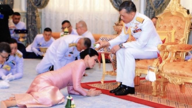 The king is seen pouring sacred water on the head of Queen Suthida