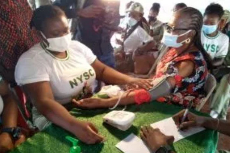 NYSC deworms 156 students, donates food items to residents NYSC corps member offering medical aid to a resident of the community