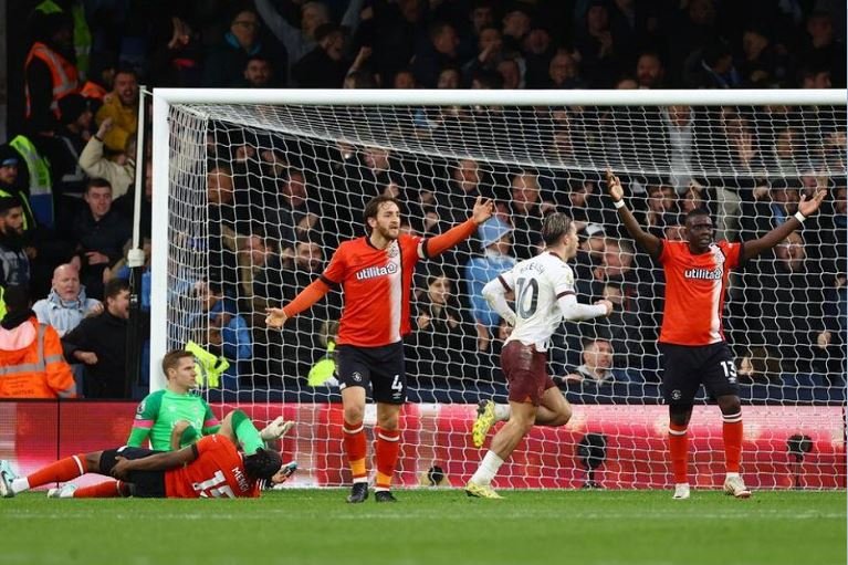 Jack Grealish wheels away after grabbing the winner for Manchester City as Luton Town players protest