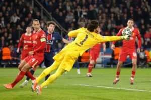 Alisson dives to punch the ball away during Liverpool's win over PSG